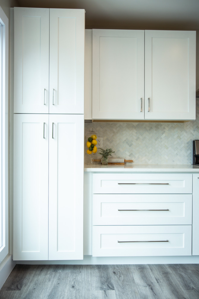 Bild på ett avskilt maritimt grå grått u-kök, med en dubbel diskho, skåp i shakerstil, vita skåp, bänkskiva i kalksten, flerfärgad stänkskydd, stänkskydd i glaskakel, integrerade vitvaror, vinylgolv, flera köksöar och grått golv