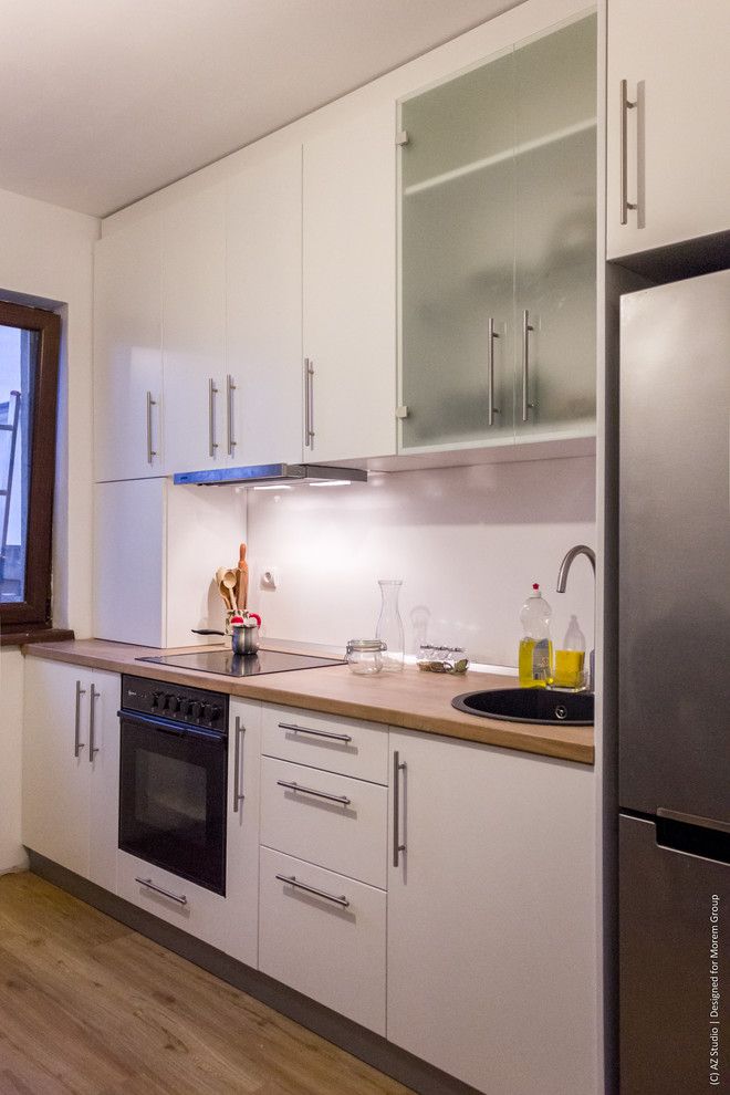 Idéer för ett avskilt, litet modernt linjärt kök, med en enkel diskho, släta luckor, vita skåp, laminatbänkskiva, vitt stänkskydd och plywoodgolv