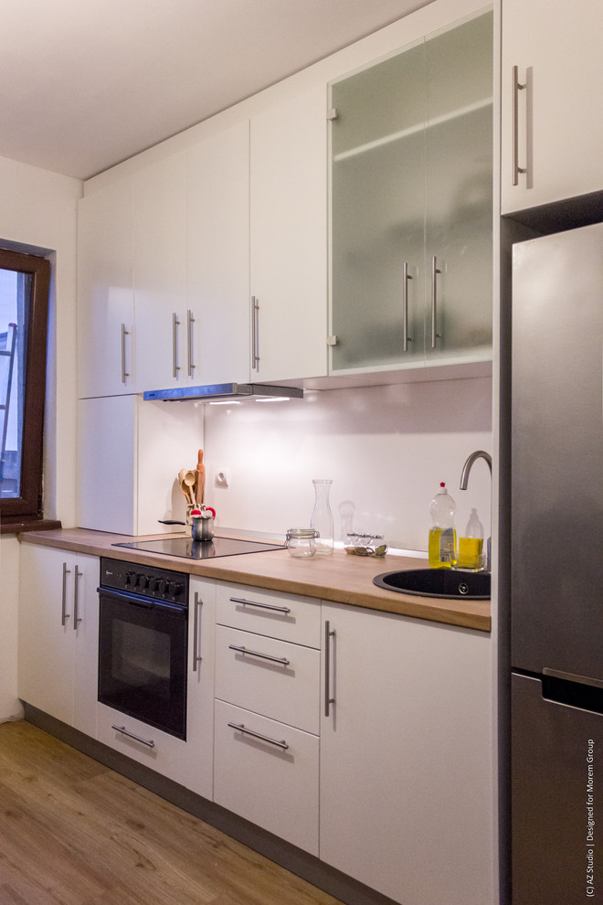 Foto de cocina lineal contemporánea pequeña cerrada sin isla con fregadero de un seno, armarios con paneles lisos, puertas de armario blancas, encimera de laminado, salpicadero blanco y suelo de contrachapado