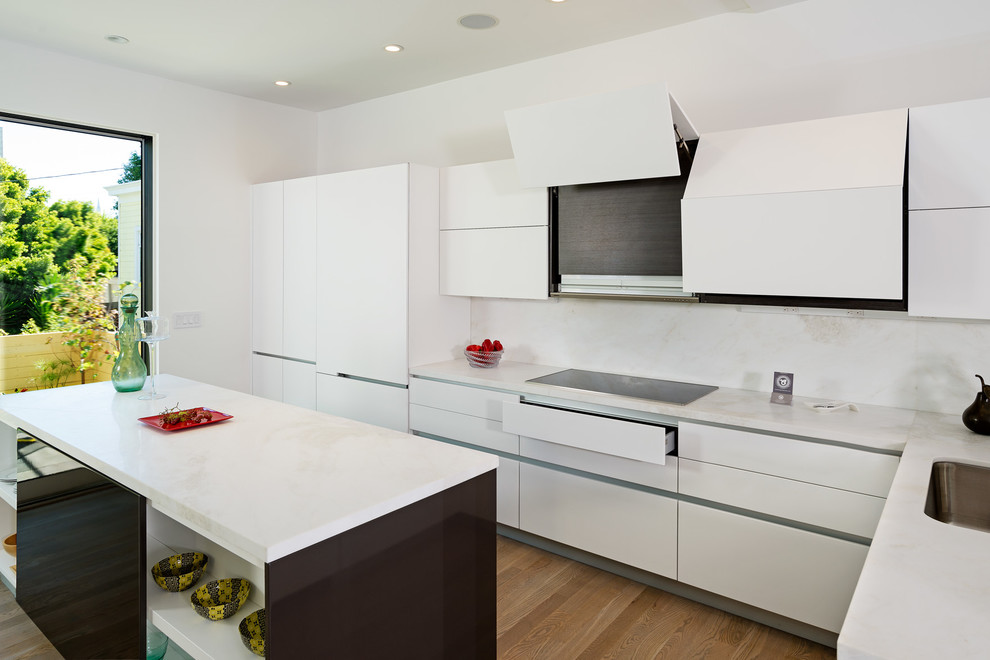 Photo of a modern l-shaped kitchen/diner in San Francisco with a submerged sink, flat-panel cabinets, white cabinets, composite countertops, white splashback, stone tiled splashback and integrated appliances.