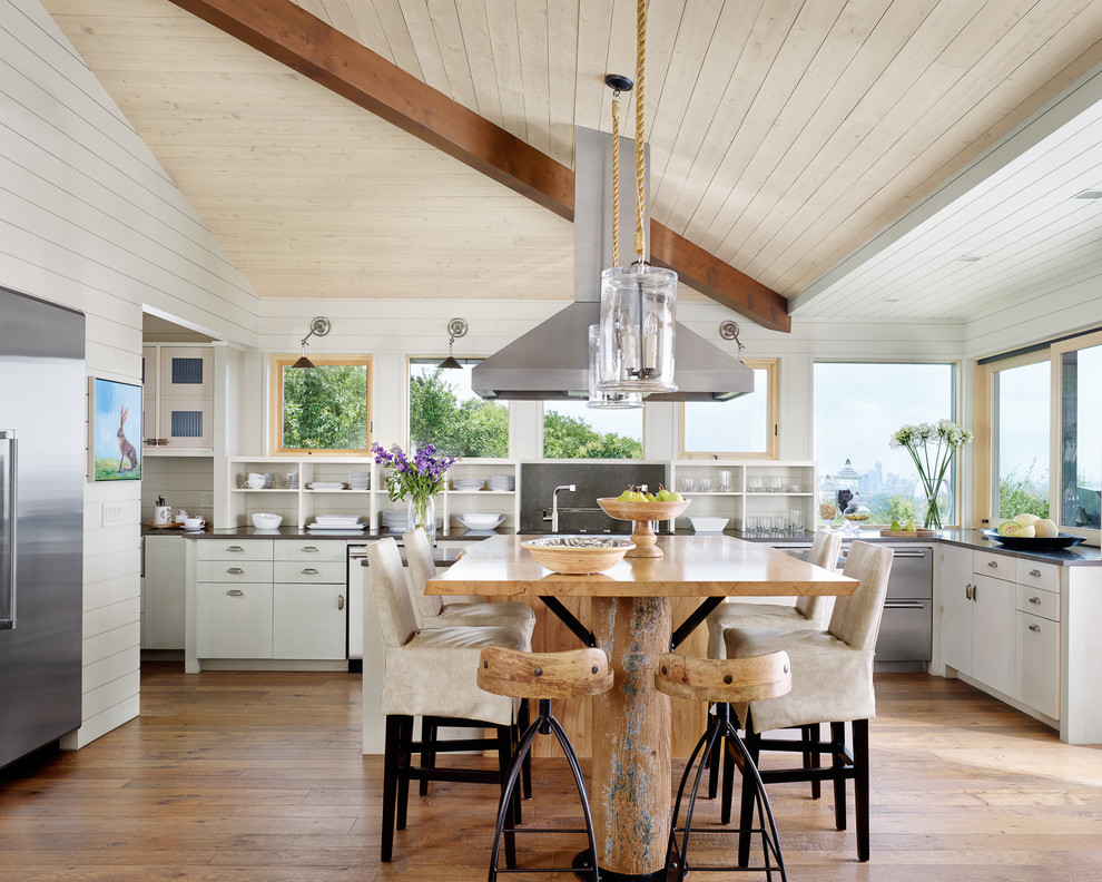 Geräumige Landhaus Wohnküche in U-Form mit flächenbündigen Schrankfronten, weißen Schränken, Küchengeräten aus Edelstahl, braunem Holzboden und Kücheninsel in Austin