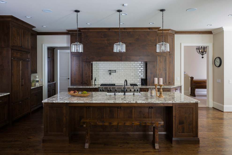 Große Klassische Küche mit dunklen Holzschränken, Granit-Arbeitsplatte, Küchenrückwand in Weiß, Rückwand aus Metrofliesen, Küchengeräten aus Edelstahl und braunem Holzboden in Atlanta