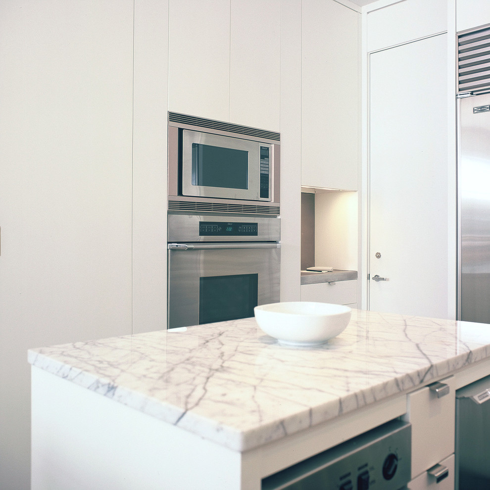 Foto di una piccola cucina minimal con lavello a doppia vasca, ante lisce, ante bianche, top in granito, elettrodomestici in acciaio inossidabile e parquet scuro