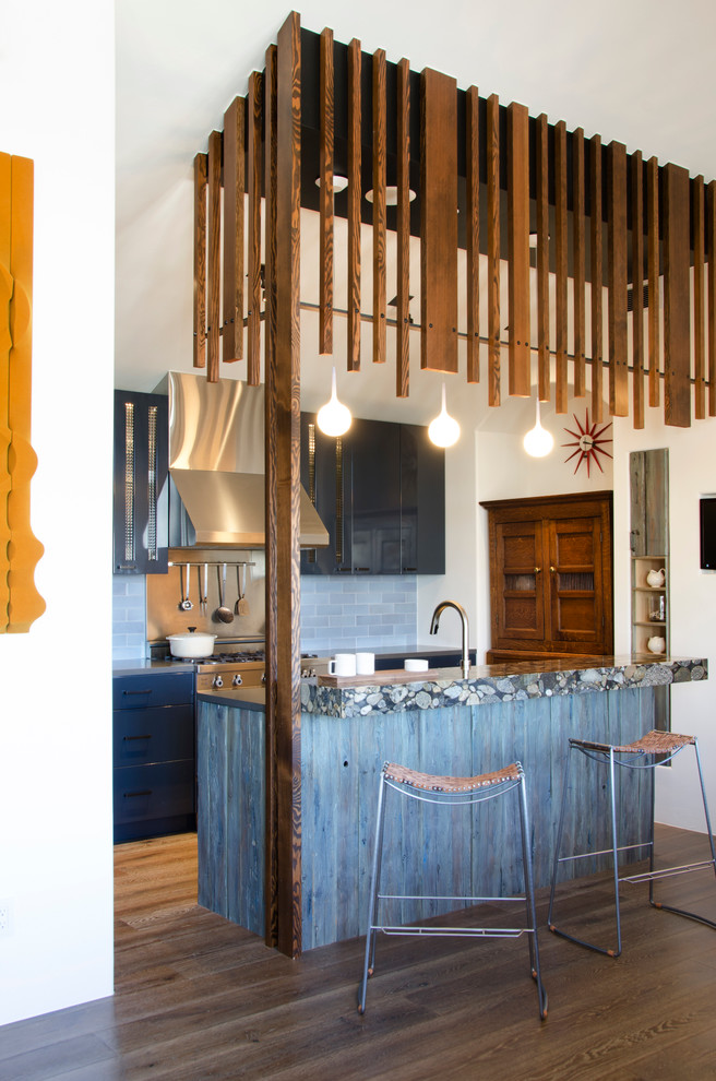 Exemple d'une cuisine parallèle tendance avec un placard à porte plane, des portes de placard grises, une crédence grise et un sol en bois brun.