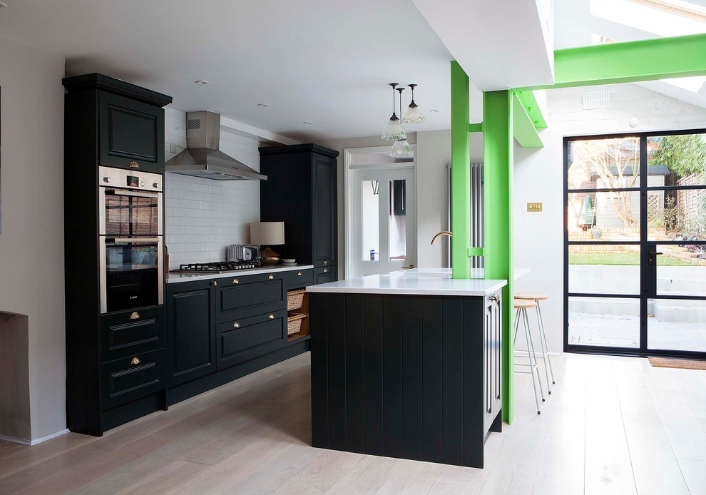 Zweizeilige Klassische Küche mit profilierten Schrankfronten, Küchengeräten aus Edelstahl, hellem Holzboden, Kücheninsel, beigem Boden und weißer Arbeitsplatte in London