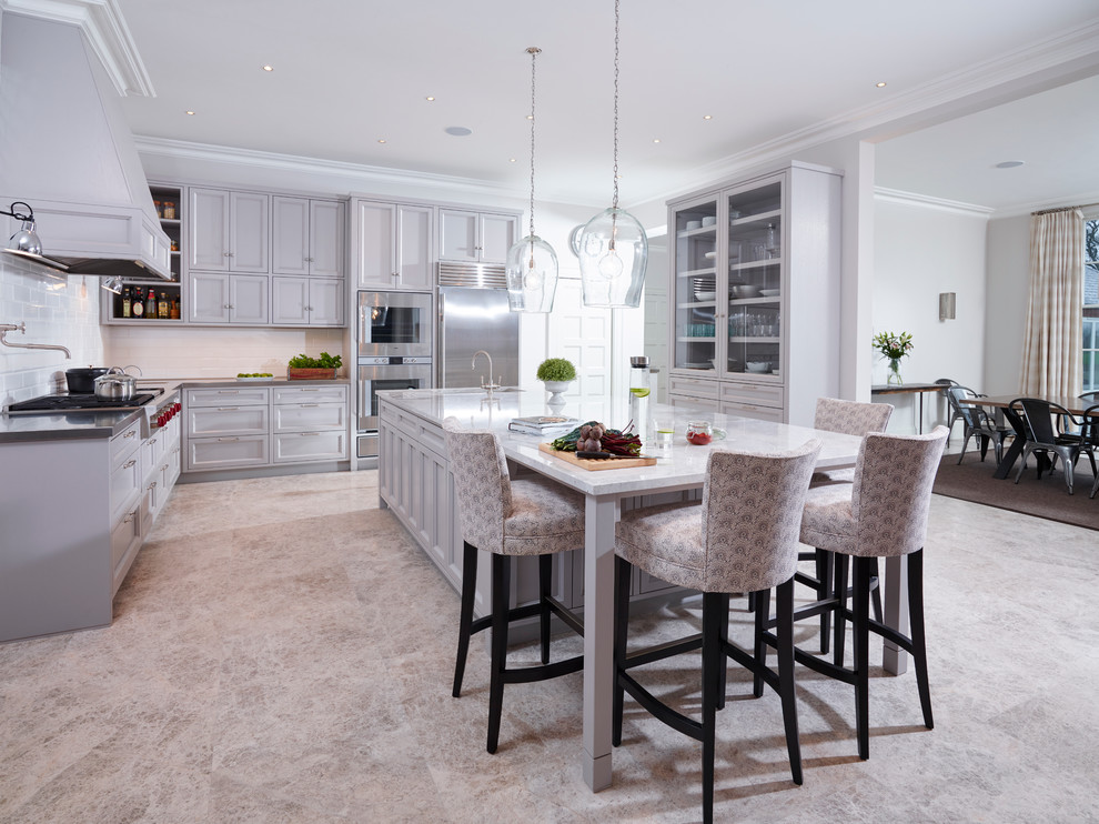 Design ideas for a traditional l-shaped enclosed kitchen in London with a single-bowl sink, grey cabinets, stainless steel worktops, white splashback, metro tiled splashback, stainless steel appliances, an island, shaker cabinets and limestone flooring.