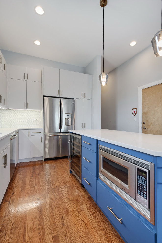 Large transitional l-shaped medium tone wood floor, brown floor and tray ceiling eat-in kitchen photo in Chicago with an undermount sink, flat-panel cabinets, gray cabinets, quartz countertops, white backsplash, porcelain backsplash, stainless steel appliances, an island and white countertops