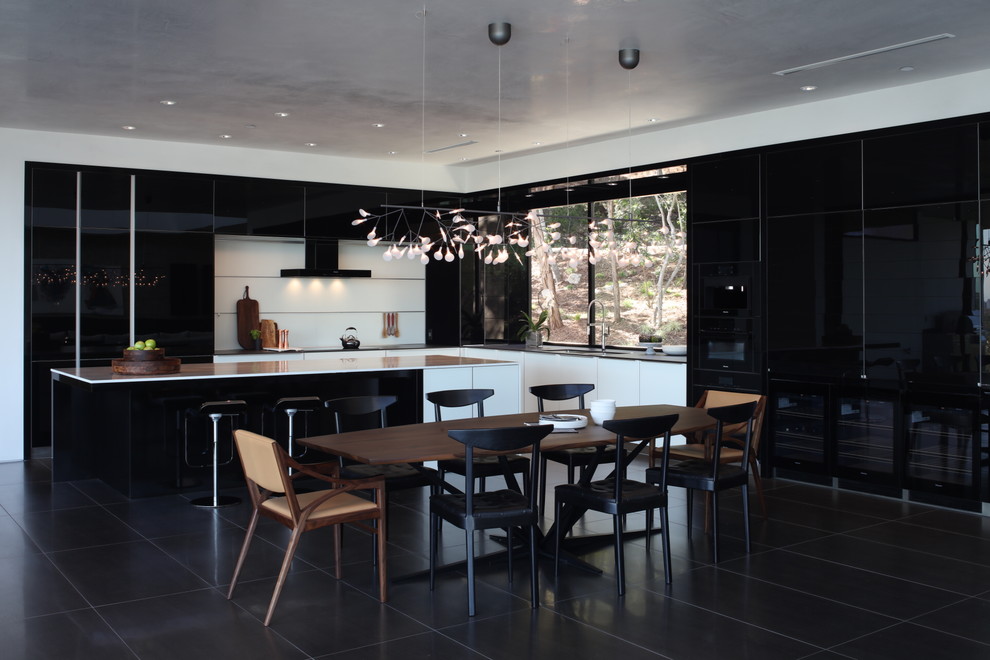 Inspiration for a contemporary l-shaped black floor and porcelain tile eat-in kitchen remodel in Austin with flat-panel cabinets, black cabinets, white backsplash, an island, an undermount sink, marble countertops, glass sheet backsplash and black appliances