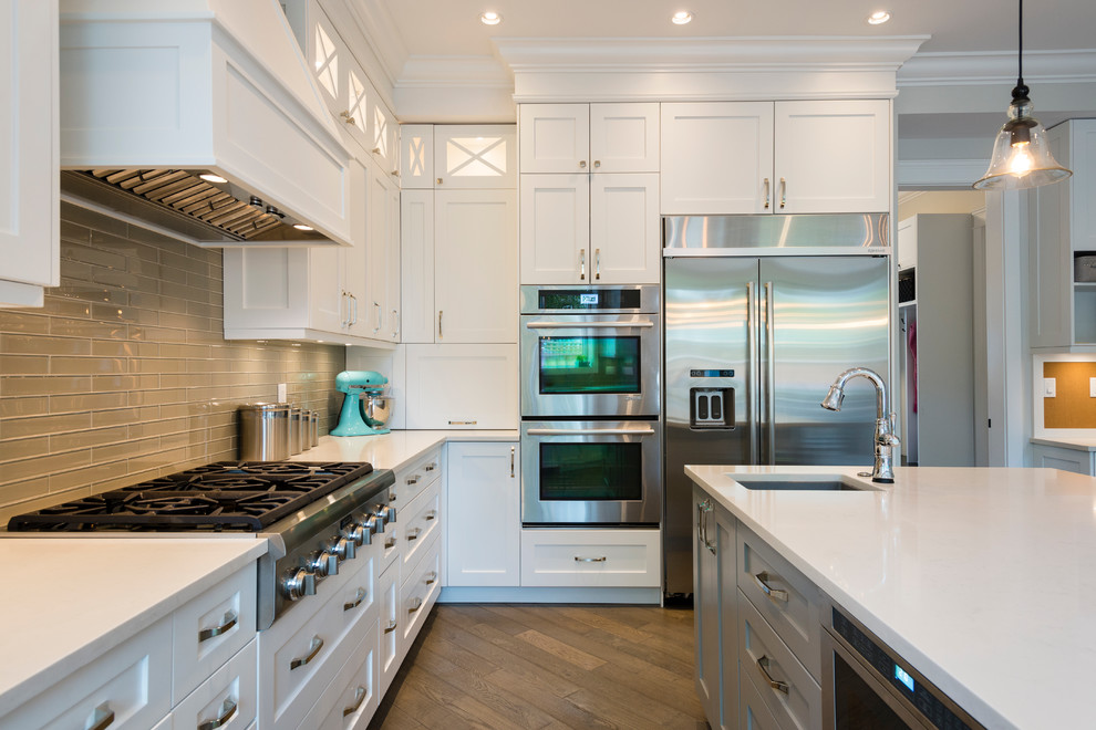 Open concept kitchen - large transitional u-shaped medium tone wood floor open concept kitchen idea in Vancouver with an undermount sink, shaker cabinets, white cabinets, quartz countertops, green backsplash, glass tile backsplash, stainless steel appliances and an island