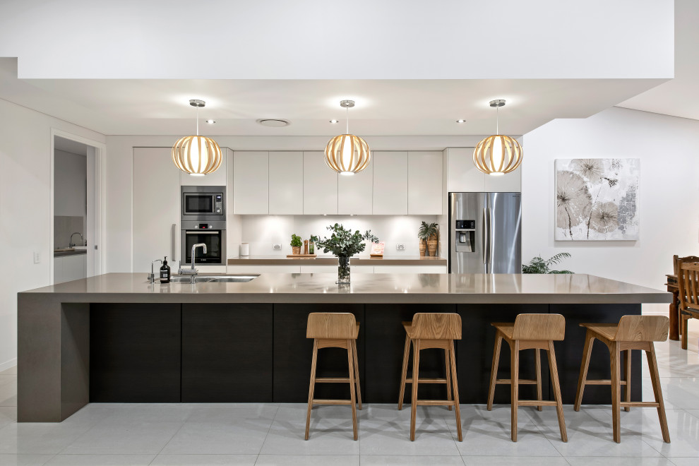 Immagine di una cucina design con lavello sottopiano, ante lisce, ante bianche, elettrodomestici in acciaio inossidabile, pavimento grigio e top grigio