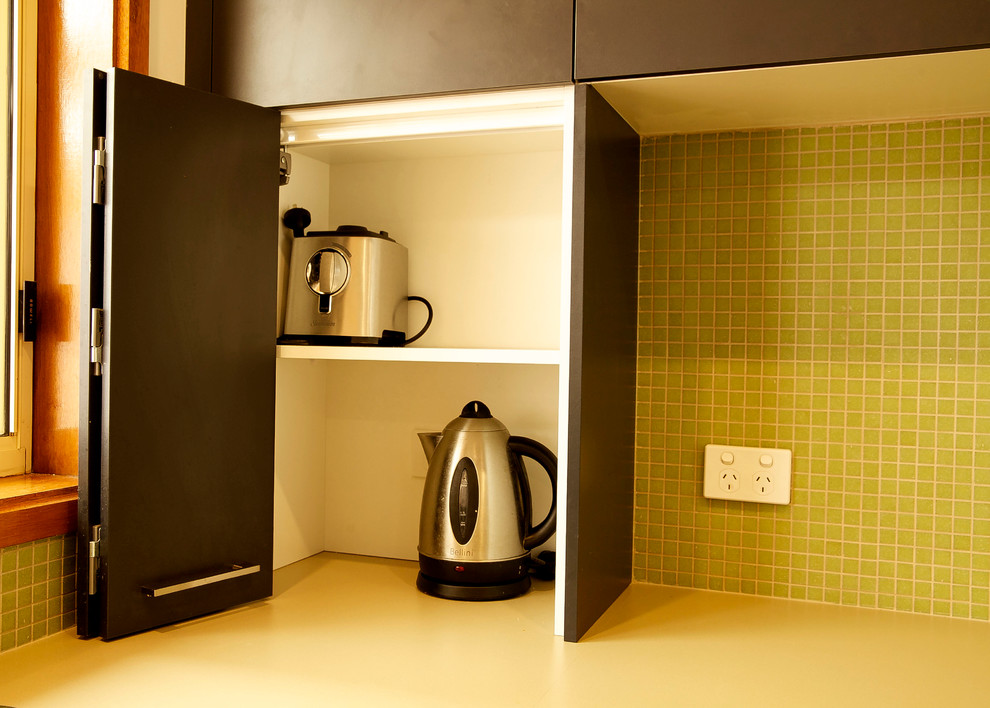 Exempel på ett litet modernt kök, med en dubbel diskho, grönt stänkskydd, stänkskydd i glaskakel, rostfria vitvaror och mellanmörkt trägolv
