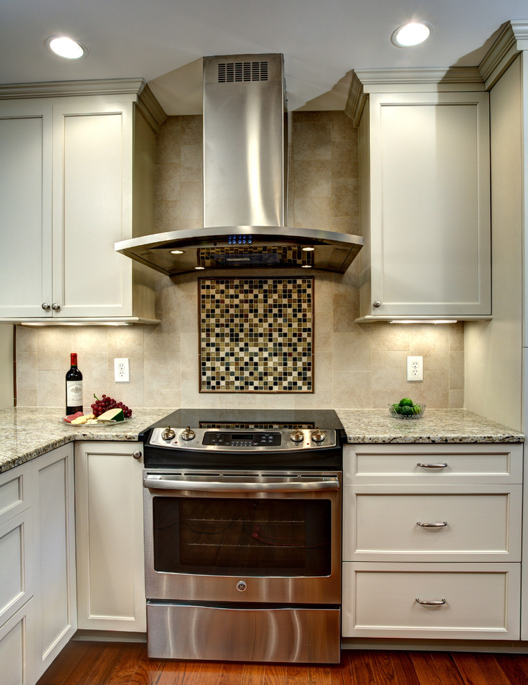 Photo of a classic l-shaped kitchen in DC Metro with recessed-panel cabinets, beige cabinets, granite worktops, stainless steel appliances and medium hardwood flooring.