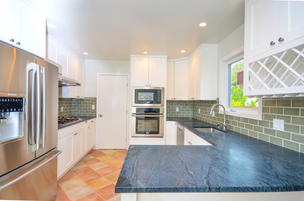 Idéer för att renovera ett mellanstort funkis blå blått kök, med en undermonterad diskho, skåp i shakerstil, vita skåp, granitbänkskiva, grått stänkskydd, stänkskydd i tunnelbanekakel, rostfria vitvaror, klinkergolv i porslin, en halv köksö och orange golv