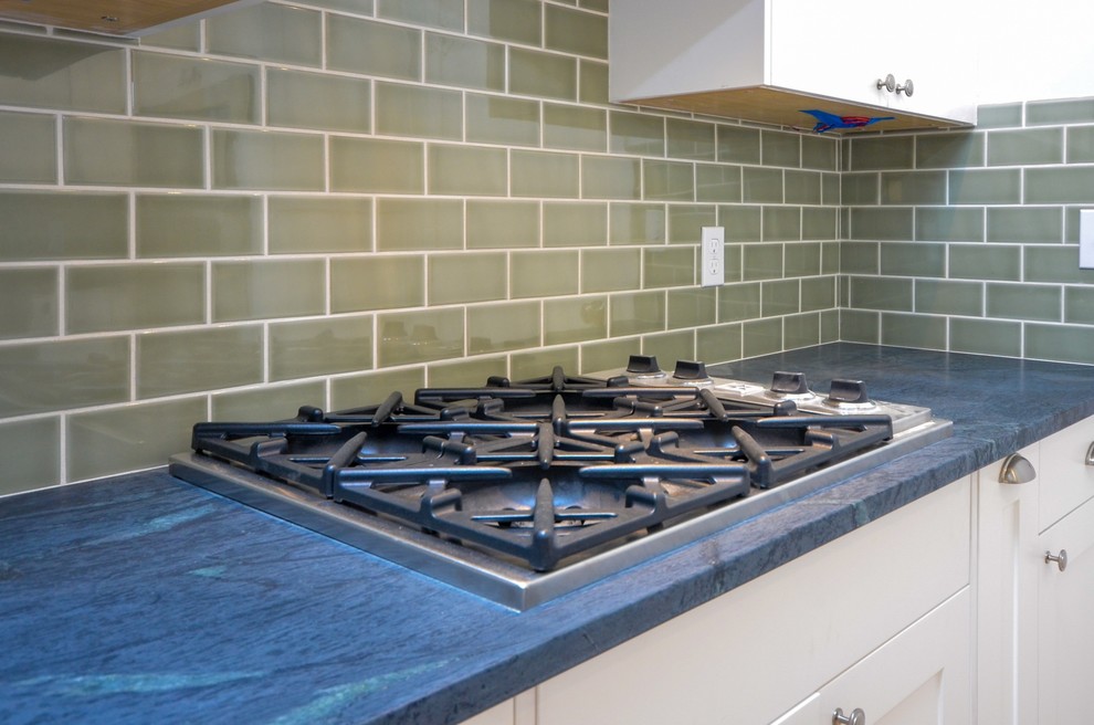 Modern inredning av ett mellanstort blå blått kök, med en undermonterad diskho, skåp i shakerstil, vita skåp, granitbänkskiva, grått stänkskydd, stänkskydd i tunnelbanekakel, rostfria vitvaror, klinkergolv i porslin, en halv köksö och orange golv