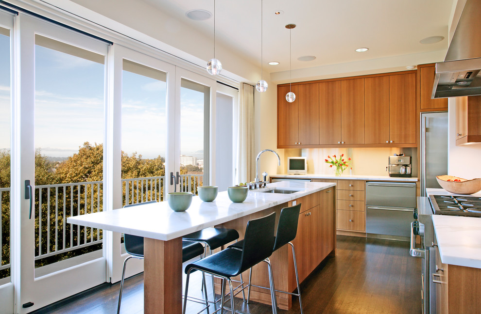 Example of a transitional l-shaped dark wood floor kitchen design in San Francisco with flat-panel cabinets, medium tone wood cabinets, white backsplash, stainless steel appliances and an island