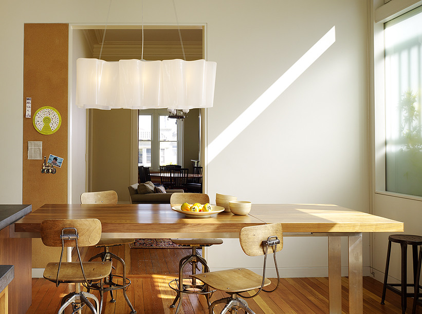 Пример оригинального дизайна: кухня в стиле модернизм с обеденным столом, плоскими фасадами, светлыми деревянными фасадами, столешницей из талькохлорита, техникой из нержавеющей стали и светлым паркетным полом