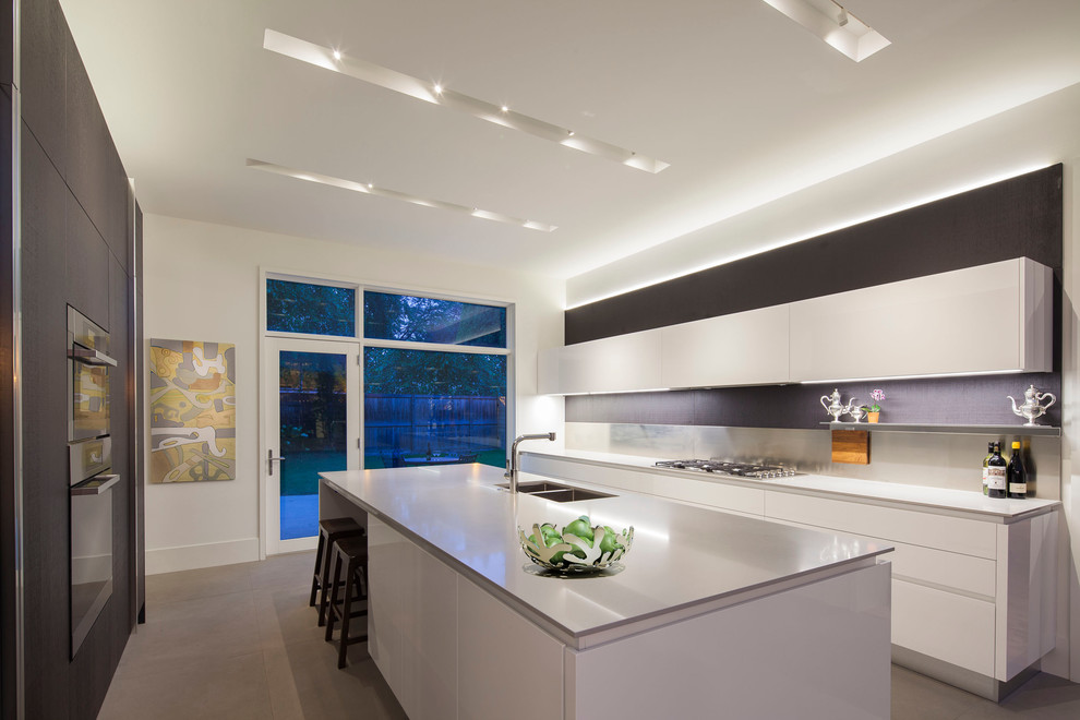 This is an example of a contemporary kitchen in Chicago with a double-bowl sink, flat-panel cabinets, white cabinets, white splashback and stainless steel appliances.