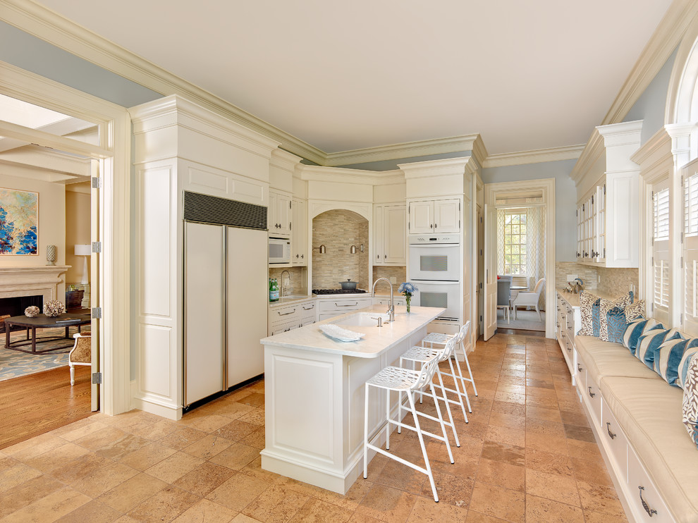 This is an example of a traditional l-shaped enclosed kitchen in Charleston with a submerged sink, raised-panel cabinets, white cabinets, multi-coloured splashback, mosaic tiled splashback, white appliances and an island.