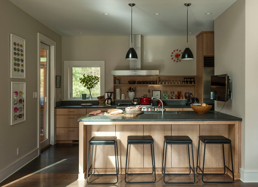 Cette image montre une cuisine parallèle traditionnelle en bois brun avec une crédence marron, un électroménager en acier inoxydable, un sol en bois brun, un sol marron et un placard à porte plane.
