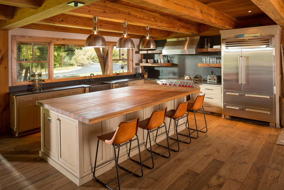 Urige Küche in L-Form mit Landhausspüle, offenen Schränken, Küchenrückwand in Grau, Küchengeräten aus Edelstahl, braunem Holzboden und Kücheninsel in Portland