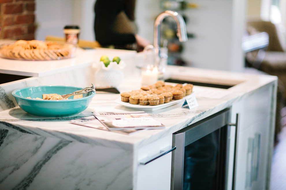 Foto på ett funkis kök, med luckor med glaspanel, vita skåp, rostfria vitvaror och en köksö