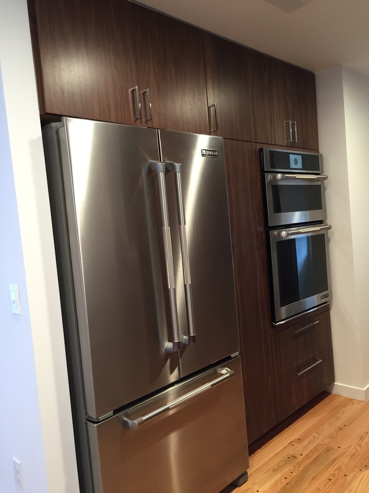 Example of a 1950s galley medium tone wood floor eat-in kitchen design in Portland with flat-panel cabinets, dark wood cabinets, stainless steel appliances and no island