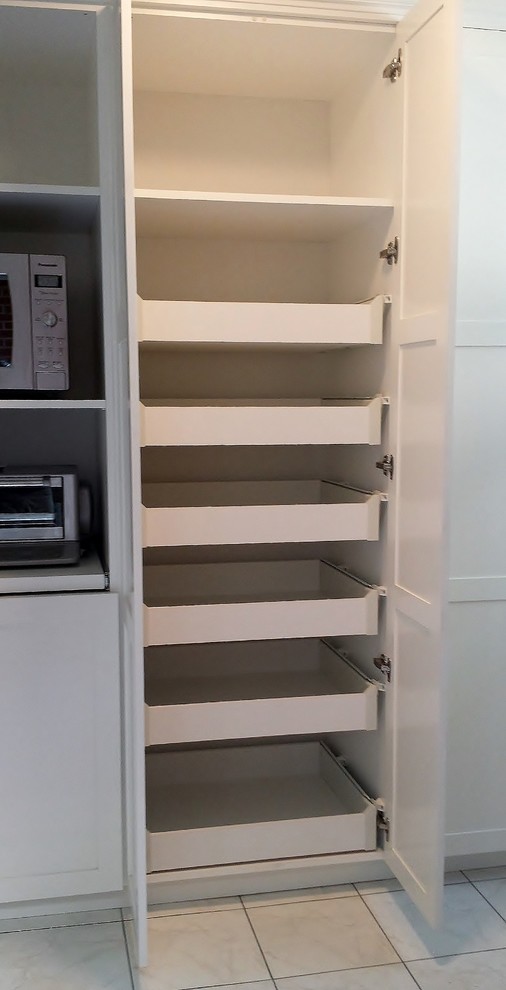Cette photo montre une arrière-cuisine linéaire tendance de taille moyenne avec un placard à porte shaker et des portes de placard blanches.