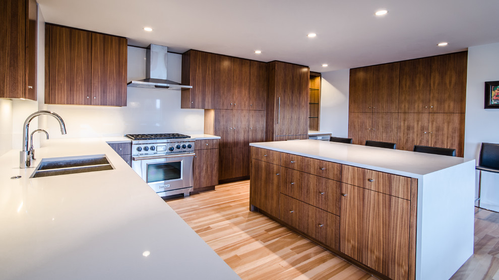 Exemple d'une grande cuisine moderne en L et bois brun avec un évier 2 bacs, un placard à porte plane, une crédence blanche, un électroménager en acier inoxydable, parquet clair et îlot.