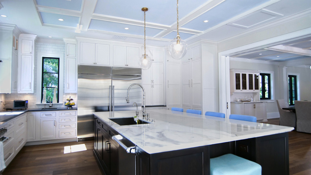 Enclosed kitchen - large contemporary u-shaped dark wood floor and brown floor enclosed kitchen idea in Miami with a drop-in sink, shaker cabinets, white cabinets, marble countertops, white backsplash, subway tile backsplash, stainless steel appliances, an island and white countertops