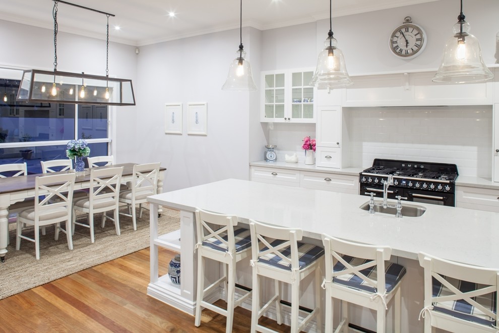 Klassische Küche mit Unterbauwaschbecken, Glasfronten, weißen Schränken, schwarzen Elektrogeräten, dunklem Holzboden und Kücheninsel in Brisbane