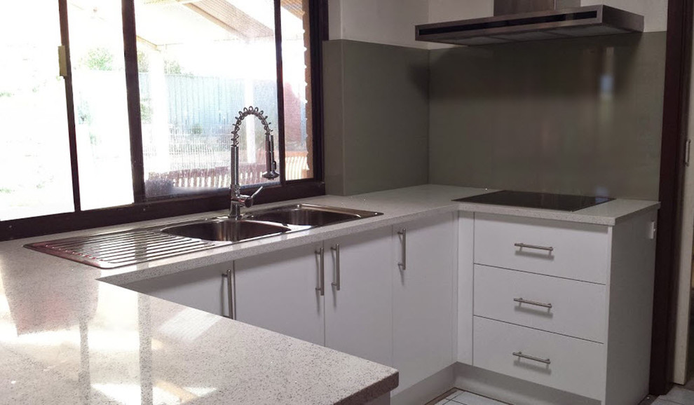 Photo of a small contemporary u-shaped enclosed kitchen in Perth with a double-bowl sink, white cabinets, engineered stone countertops, grey splashback, glass sheet splashback and stainless steel appliances.