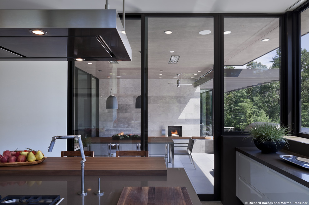 Foto di una grande cucina minimalista con ante lisce, ante bianche, top in superficie solida, paraspruzzi nero, elettrodomestici da incasso e pavimento in ardesia
