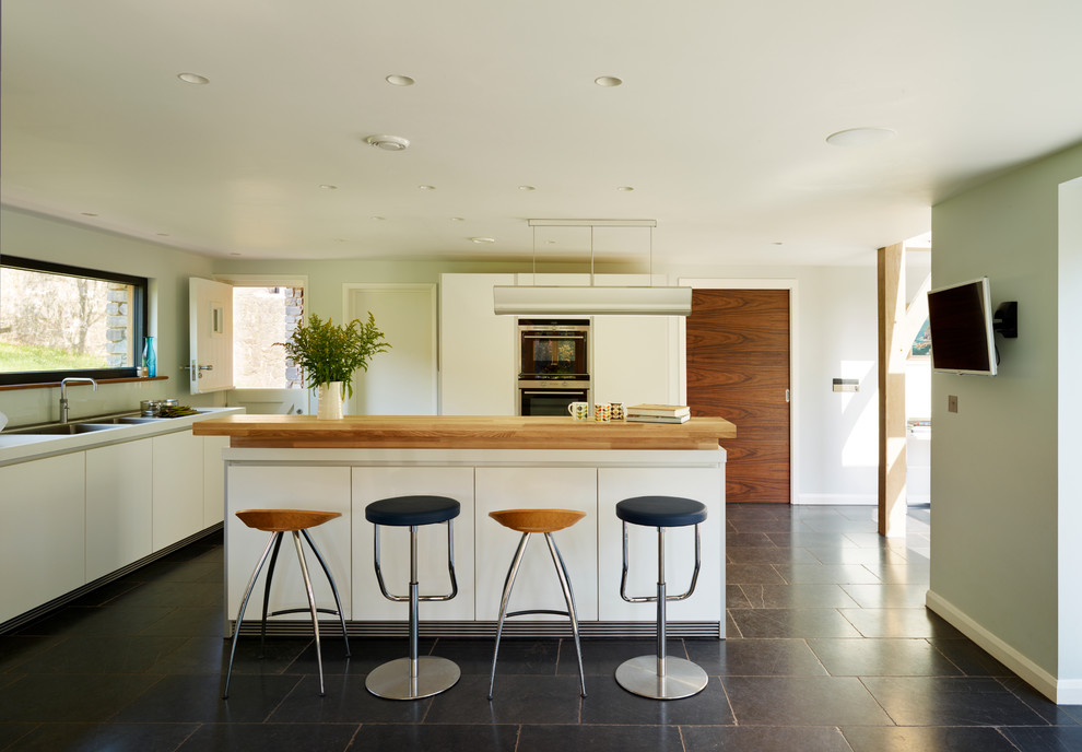 Moderne Küche in L-Form mit flächenbündigen Schrankfronten, weißen Schränken und Kücheninsel in Devon