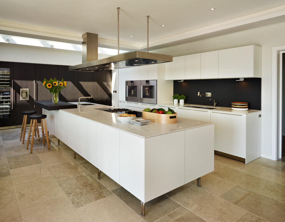 Contemporary galley kitchen in Devon with a submerged sink, flat-panel cabinets, black splashback, stainless steel appliances and an island.