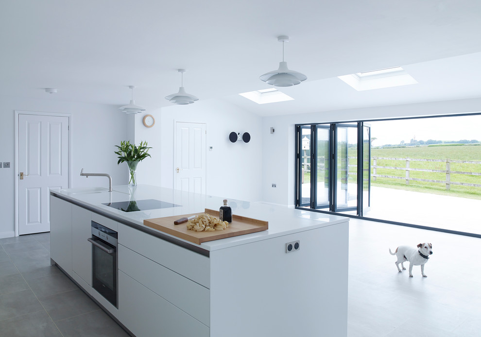 Moderne Küche mit flächenbündigen Schrankfronten, weißen Schränken und Kücheninsel in Devon