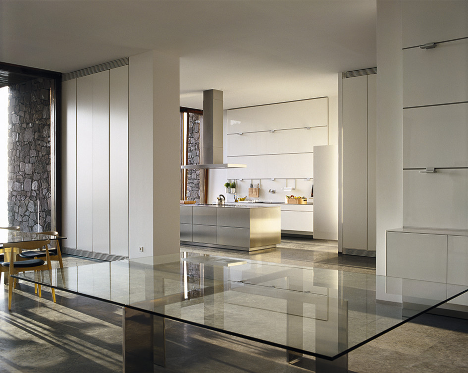 Esempio di una cucina minimal con lavello integrato, ante lisce, ante bianche, top in acciaio inossidabile, paraspruzzi bianco, paraspruzzi con lastra di vetro e pavimento in cemento