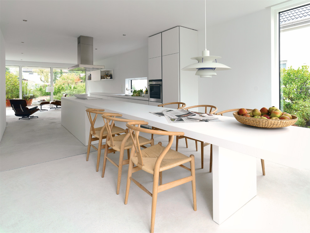 Inspiration for a medium sized contemporary galley open plan kitchen in Melbourne with a submerged sink, flat-panel cabinets, white cabinets, stainless steel appliances, an island, white splashback and concrete flooring.