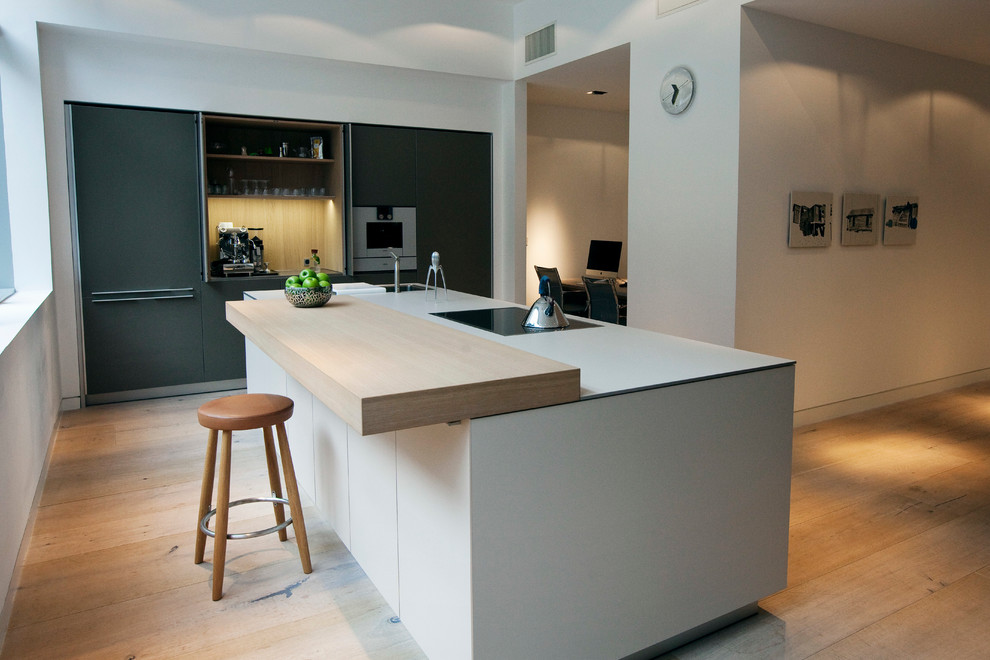 This is an example of a contemporary kitchen in Dublin with flat-panel cabinets, stainless steel appliances and light hardwood flooring.