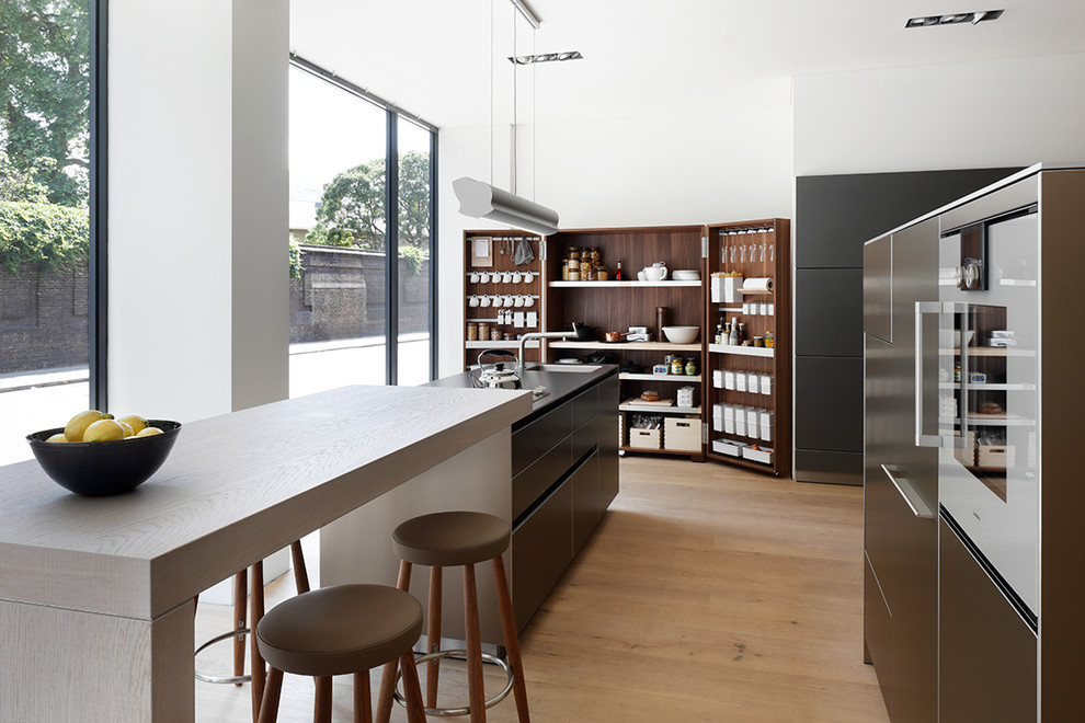 Offene, Einzeilige, Mittelgroße Moderne Küche mit flächenbündigen Schrankfronten, Mineralwerkstoff-Arbeitsplatte, Kücheninsel und braunem Holzboden in London