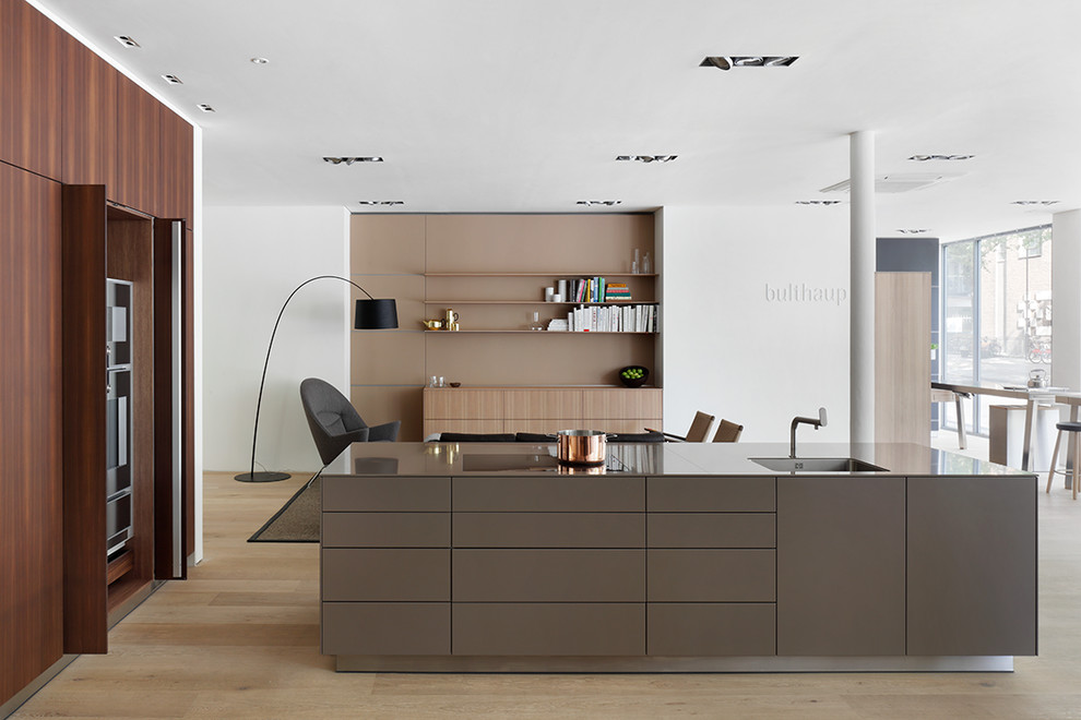 Medium sized contemporary single-wall open plan kitchen in London with an integrated sink, flat-panel cabinets, composite countertops and an island.