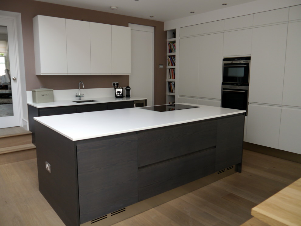 Inspiration for a medium sized contemporary u-shaped kitchen/diner in London with a single-bowl sink, engineered stone countertops, white splashback, stainless steel appliances, painted wood flooring and an island.