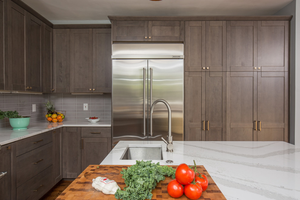 This is an example of a large contemporary u-shaped kitchen/diner in DC Metro with a submerged sink, shaker cabinets, grey cabinets, engineered stone countertops, grey splashback, porcelain splashback, stainless steel appliances, medium hardwood flooring and an island.