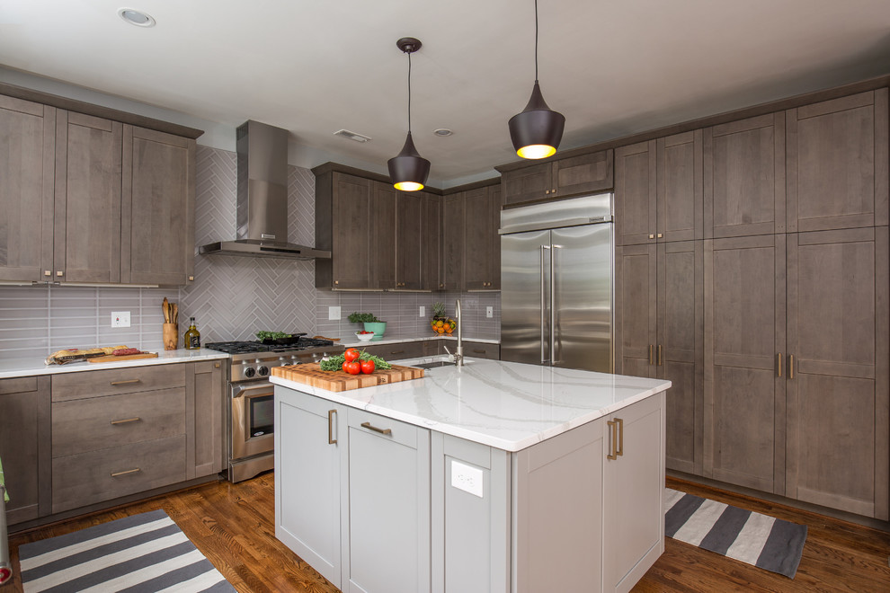 Photo of a large contemporary u-shaped kitchen/diner in DC Metro with a submerged sink, shaker cabinets, grey cabinets, engineered stone countertops, grey splashback, porcelain splashback, stainless steel appliances, medium hardwood flooring and an island.