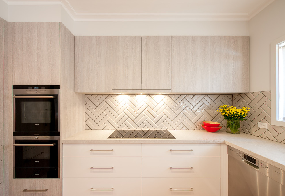 This is an example of a large contemporary u-shaped kitchen/diner in Melbourne with a single-bowl sink, flat-panel cabinets, light wood cabinets, engineered stone countertops, grey splashback, porcelain splashback, stainless steel appliances, medium hardwood flooring and no island.