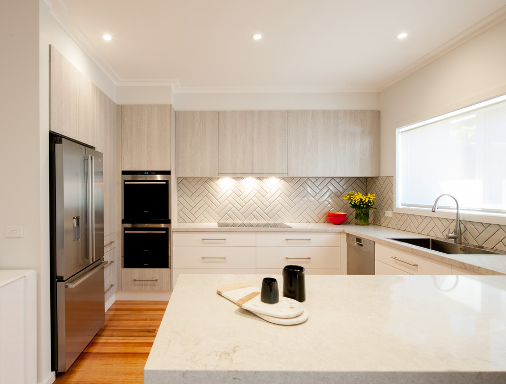 Example of a large trendy u-shaped medium tone wood floor eat-in kitchen design in Melbourne with a single-bowl sink, flat-panel cabinets, light wood cabinets, quartz countertops, gray backsplash, porcelain backsplash, stainless steel appliances and no island