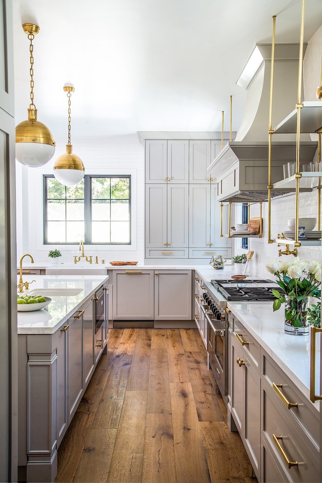 Example of a mid-sized transitional medium tone wood floor enclosed kitchen design in Los Angeles with white backsplash, subway tile backsplash, stainless steel appliances, an island, shaker cabinets and beige cabinets