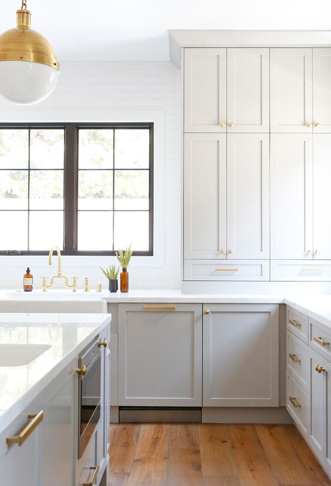 Immagine di una cucina chic di medie dimensioni con paraspruzzi bianco, paraspruzzi con piastrelle diamantate, elettrodomestici in acciaio inossidabile e pavimento in legno massello medio