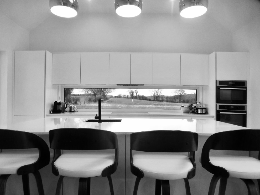Esempio di una cucina di medie dimensioni con ante lisce, ante bianche, top in quarzo composito, paraspruzzi multicolore, paraspruzzi con lastra di vetro, elettrodomestici neri, pavimento in cemento, pavimento multicolore e top bianco