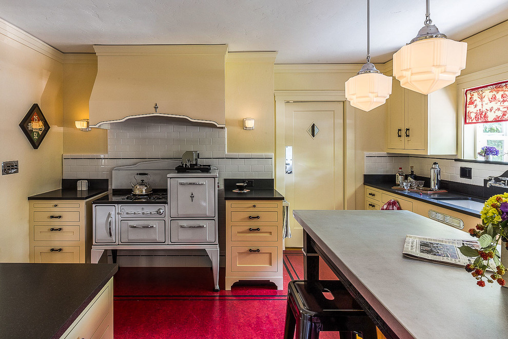 サクラメントにある高級な中くらいなトラディショナルスタイルのおしゃれなキッチン (アンダーカウンターシンク、シェーカースタイル扉のキャビネット、黄色いキャビネット、御影石カウンター、白いキッチンパネル、セラミックタイルのキッチンパネル、白い調理設備、リノリウムの床、赤い床、黒いキッチンカウンター) の写真