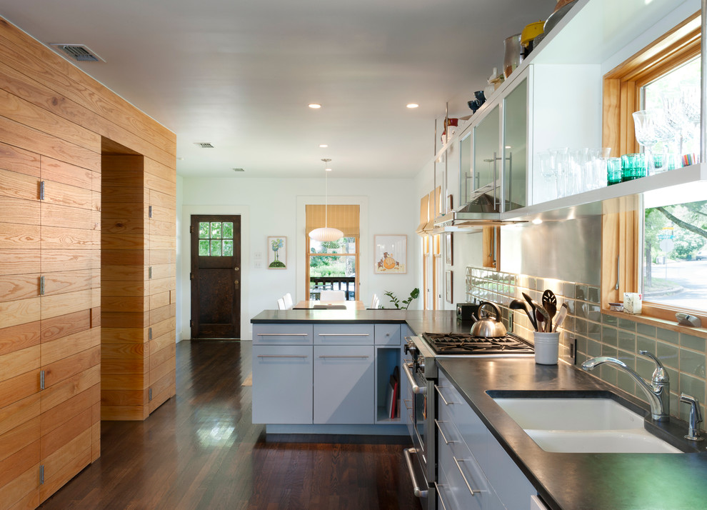 Diseño de cocina actual con armarios con paneles lisos, electrodomésticos de acero inoxidable, puertas de armario azules, salpicadero gris y fregadero de doble seno